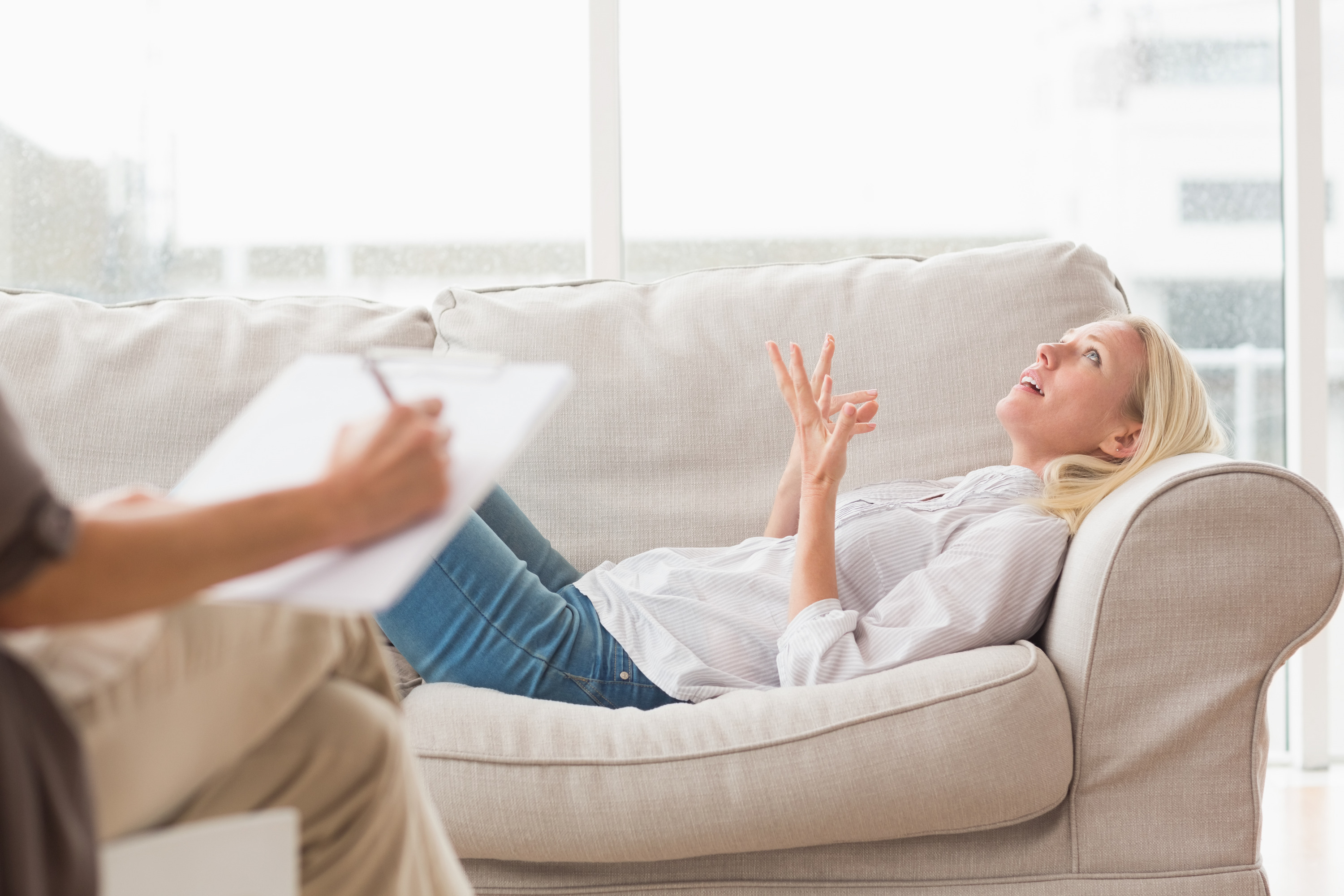 Depressed woman speaking to therapist while she is taking notes