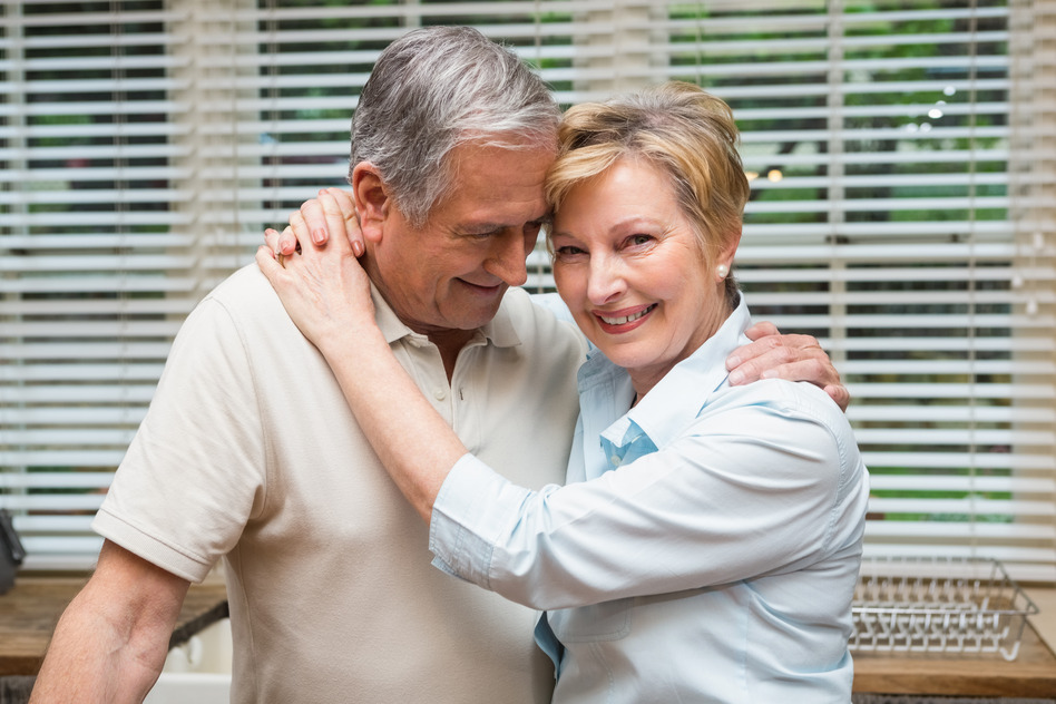 Senior couple hugging and smiling at home in the kitchen