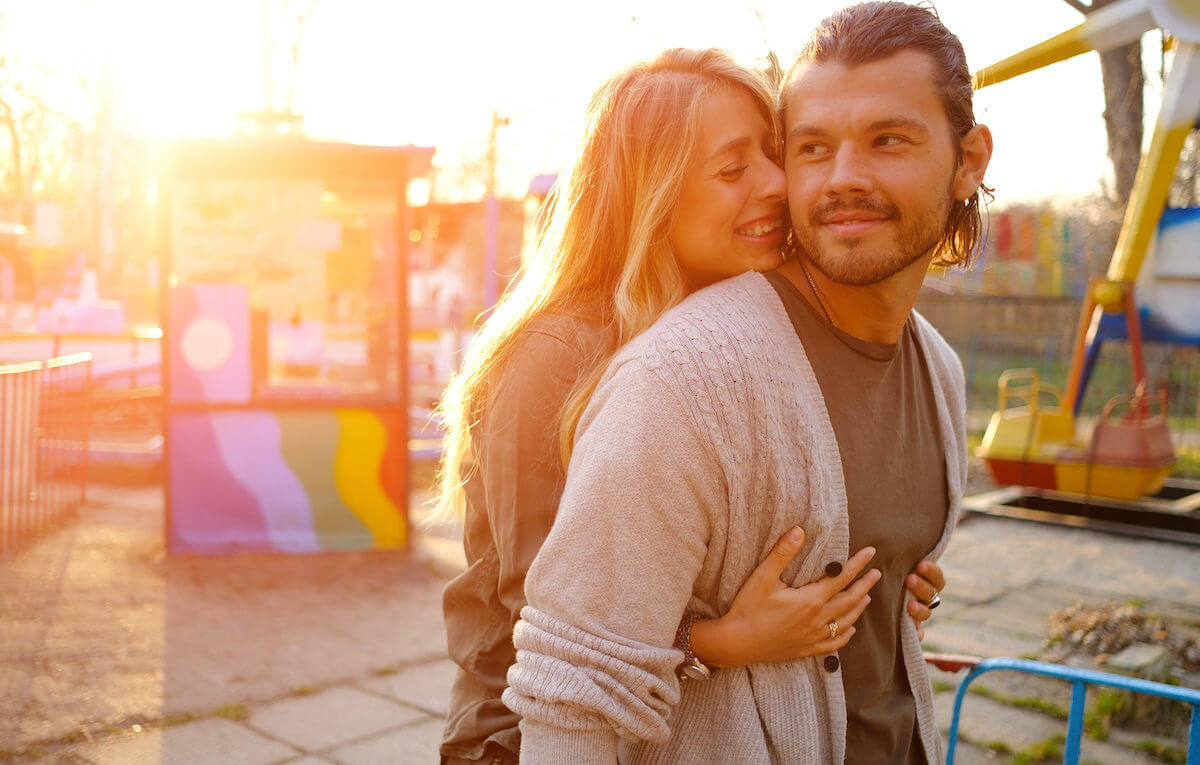 The man feels so happy while the woman hugs him from behind