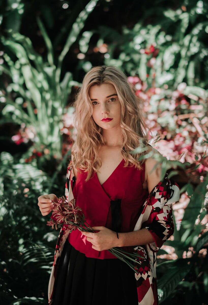 Woman Holding Flowers In Front Of The Garden