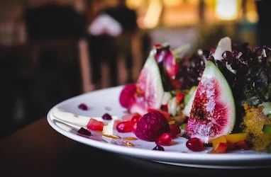 A side view of a plate of figs and berries. 